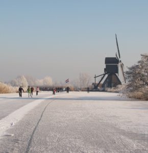 Foto Oudendijkse molen als achtergrond van de schaatsers op de Giessen